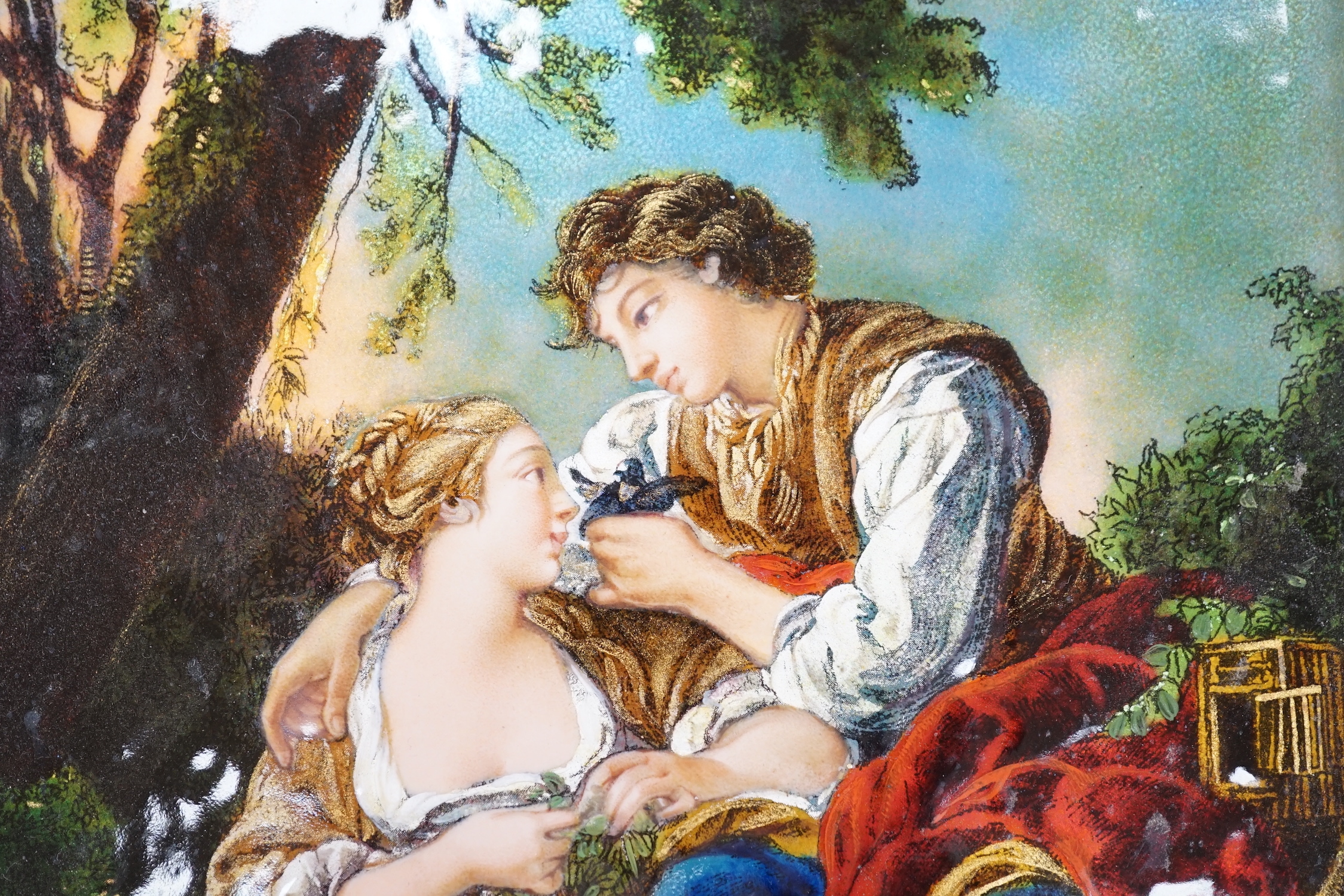 A Limoges enamel plaque, decorated with two lovers wearing 18th century dress before a landscape, housed in a gilt frame, 25cm x 19cm excluding the frame